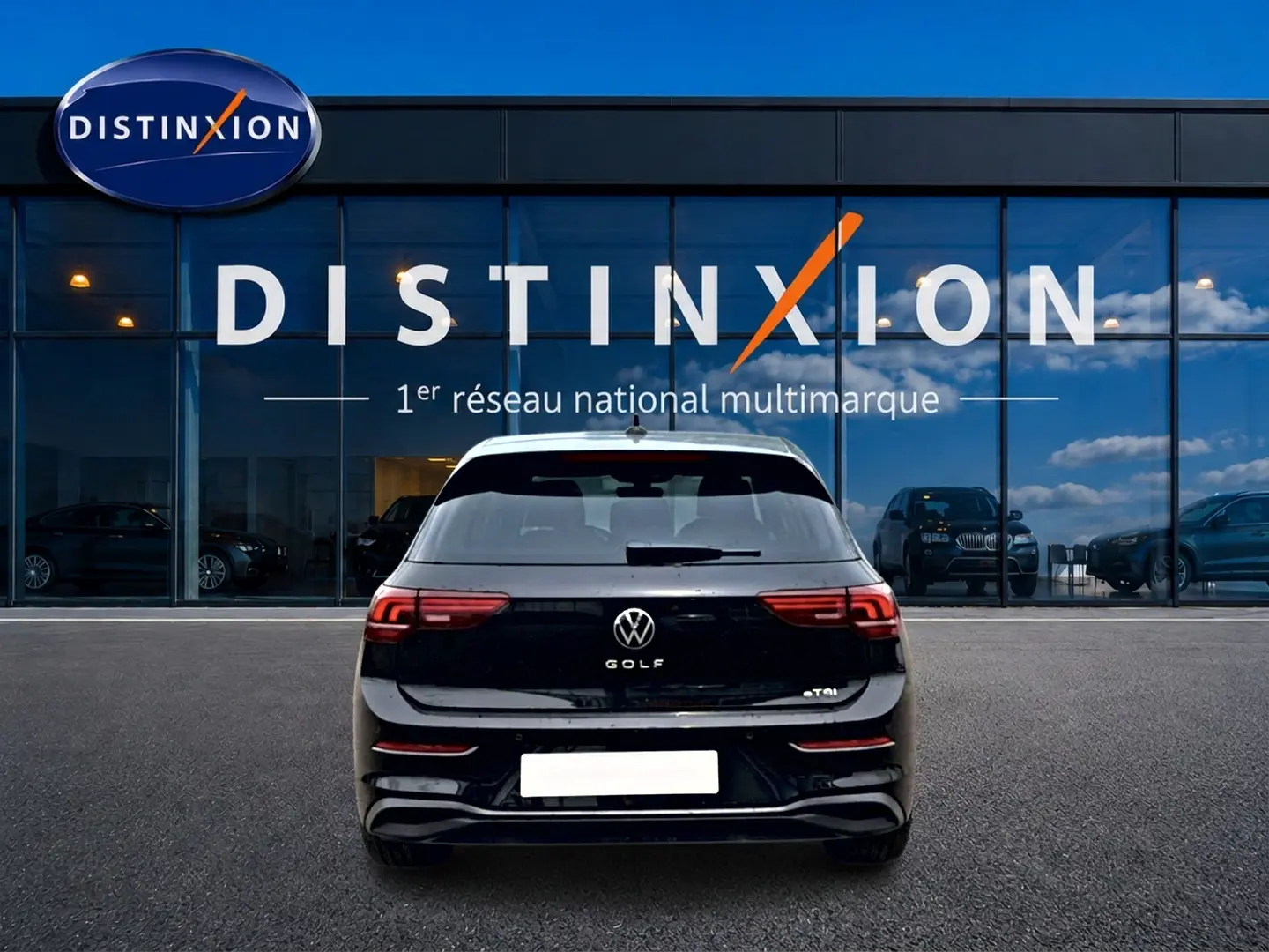 Vue arrière d'une Volkswagen Golf noire 2026 garée devant une vitrine avec logo Distinxion.