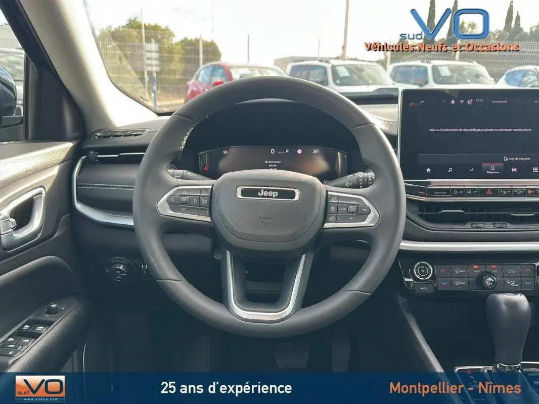 Vue frontale intérieure du volant Jeep Compass gris 2024 avec tableau de bord numérique et écran tactile central.