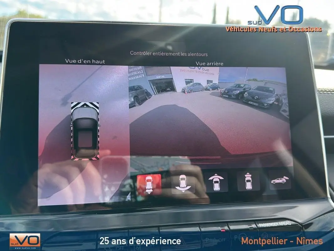 Écran tactile du Jeep Compass gris 2024 montrant la caméra de recul avec vue arrière et vue d’en haut du véhicule.