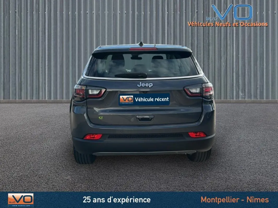 Vue arrière d'un Jeep Compass gris 2024 avec feux LED et logo Jeep bien visible sur un fond neutre.