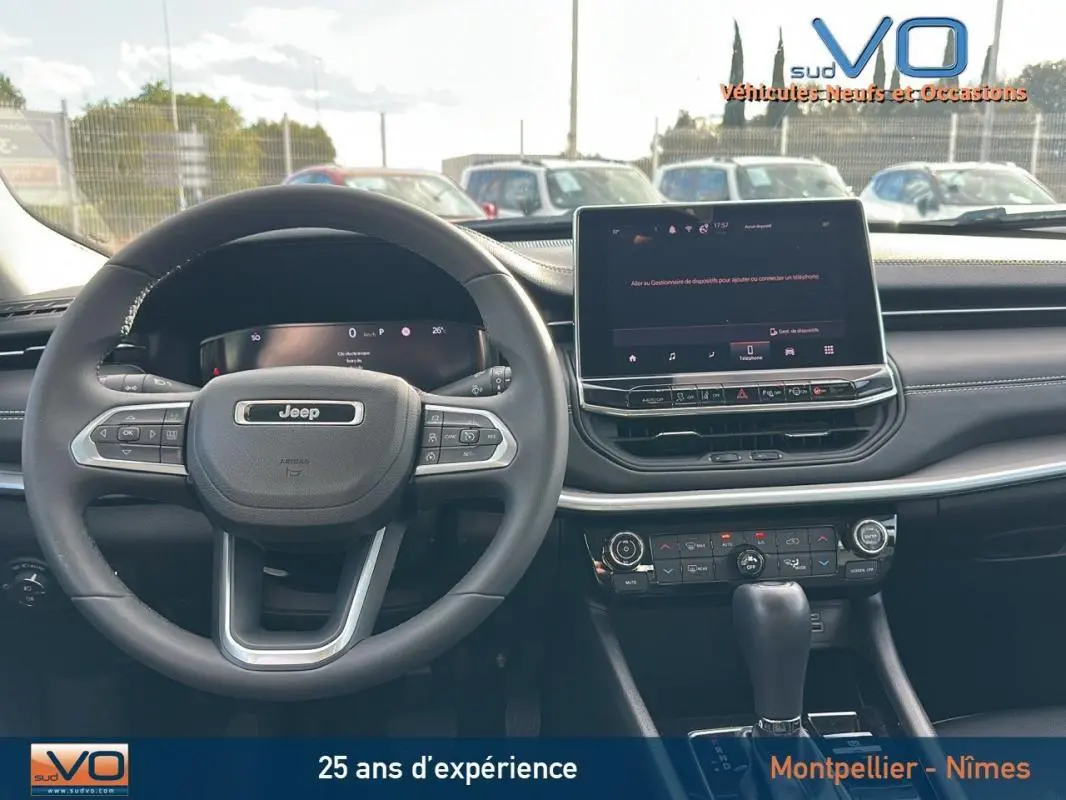 Vue intérieure du tableau de bord du Jeep Compass gris 2024 avec volant multifonction et écran tactile central.