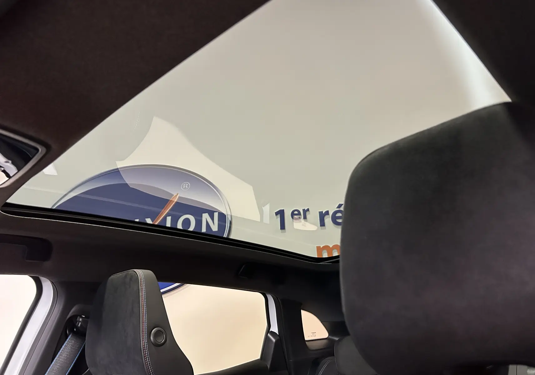 Vue intérieure du toit panoramique en verre du Renault Austral blanc nacré, avec sièges avant en cuir et alcantara noirs.