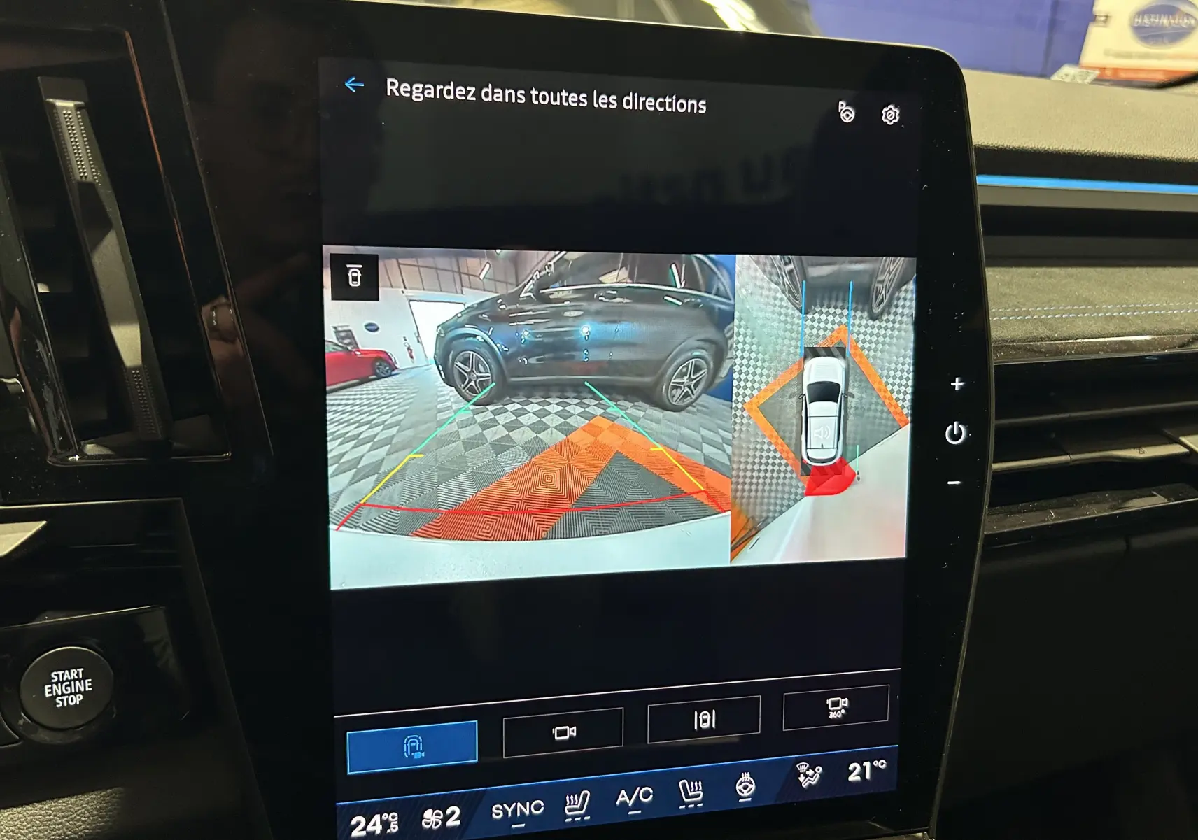 Écran tactile du Renault Austral Ph.2 blanc nacré montrant la caméra 360° avec vue arrière et vue aérienne du véhicule.