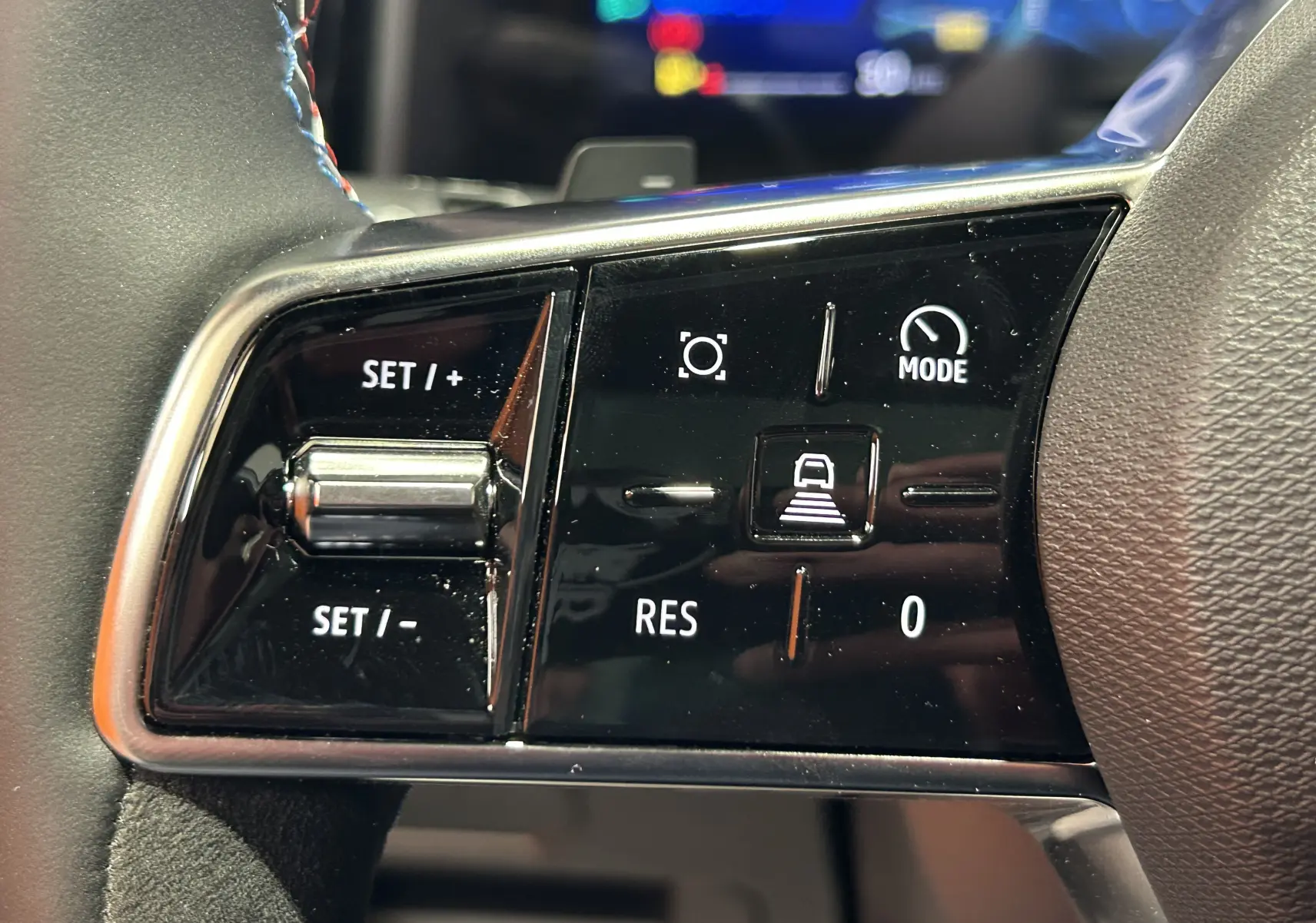 Gros plan sur les commandes de régulateur de vitesse au volant du Renault Austral blanc nacré satin.