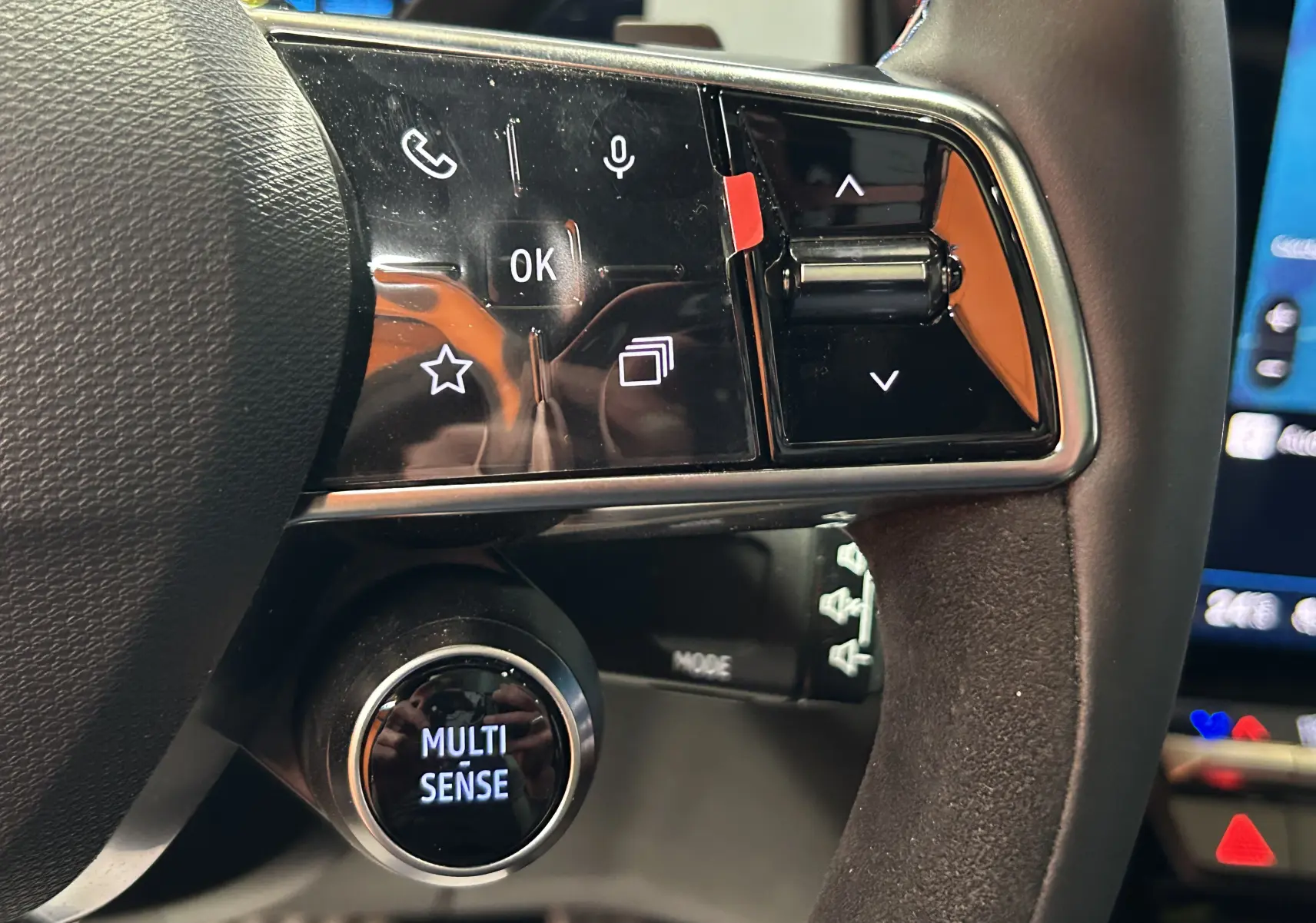 Gros plan sur les commandes noires brillantes au volant du Renault Austral blanc nacré satin, avec bouton Multi Sense éclairé.