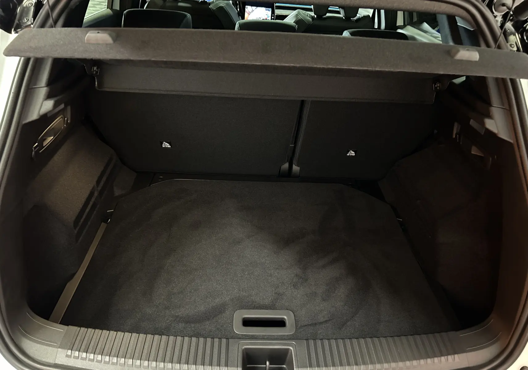 Coffre ouvert vu de l'arrière du Renault Austral blanc nacré satin, montrant un espace de chargement propre et spacieux.