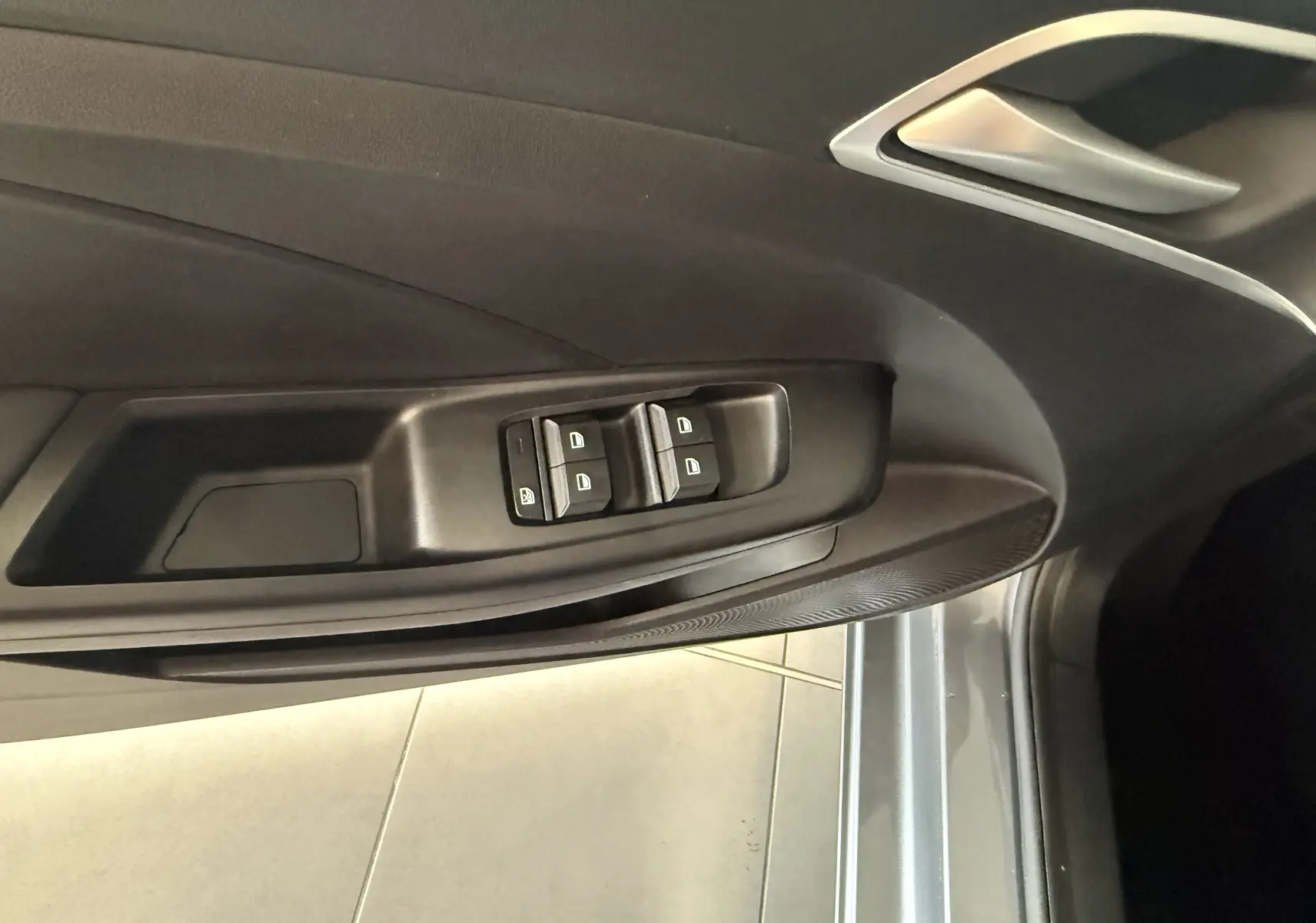 Vue rapprochée de la porte côté conducteur du MG3 2025 gris Hampstead, avec commandes électriques des vitres et poignée argentée.