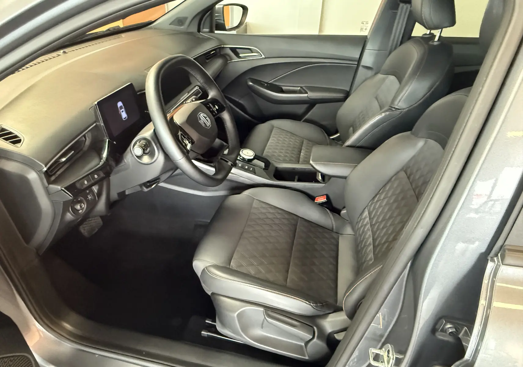Intérieur avant droit du MG3 2025 gris hampstead, sièges similicuir et tissu avec console centrale et écran tactile.