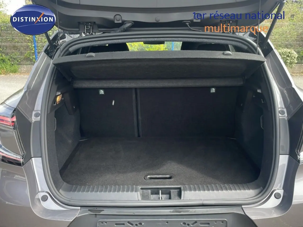 Coffre ouvert vu de l'arrière d'un Renault Captur 2025 gris Cassiopée métal avec toit noir, montrant l'espace de chargement vide.