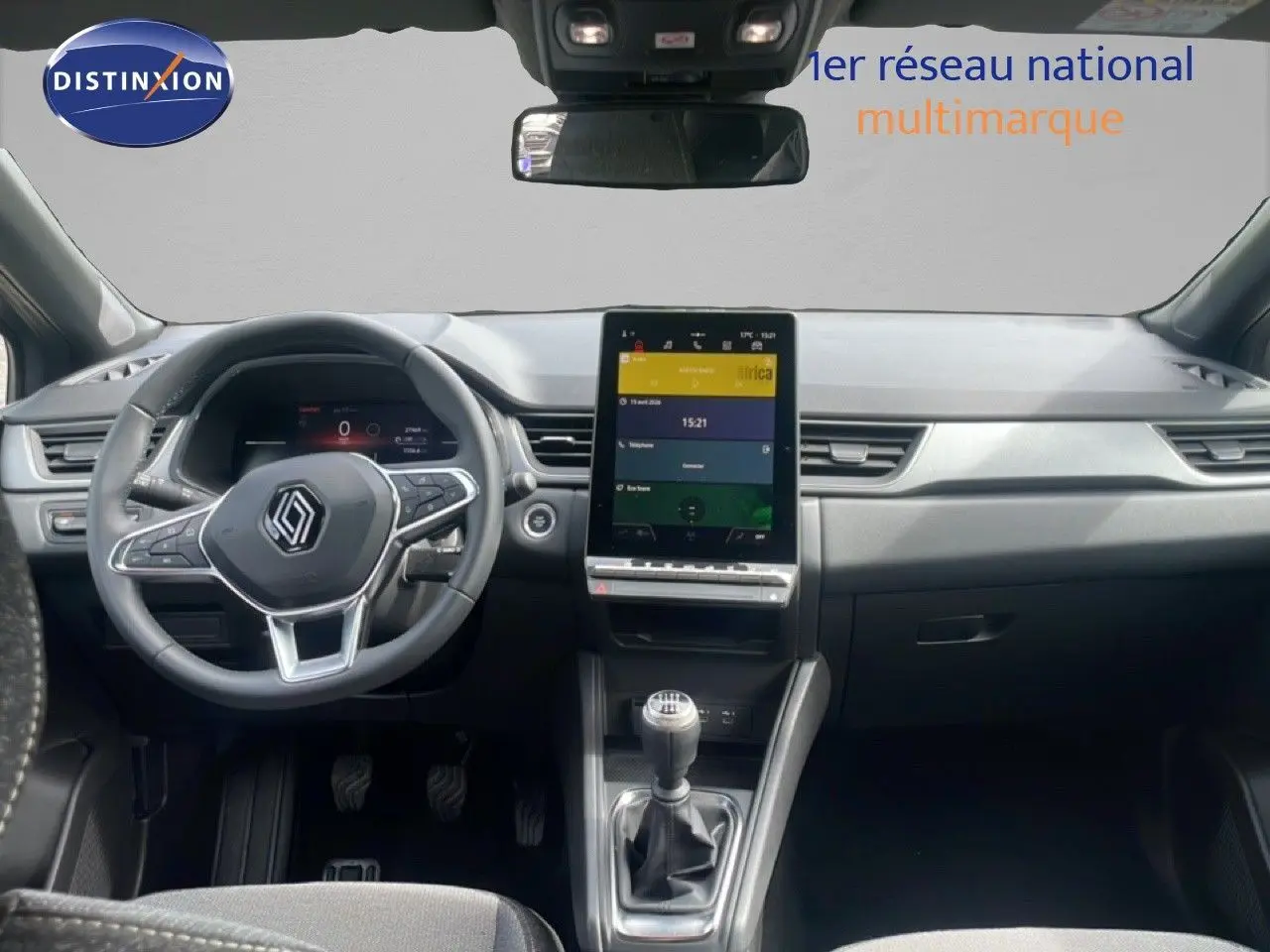 Vue intérieure avant du Renault Captur 2025, tableau de bord noir avec écran tactile vertical et levier de vitesse manuel.