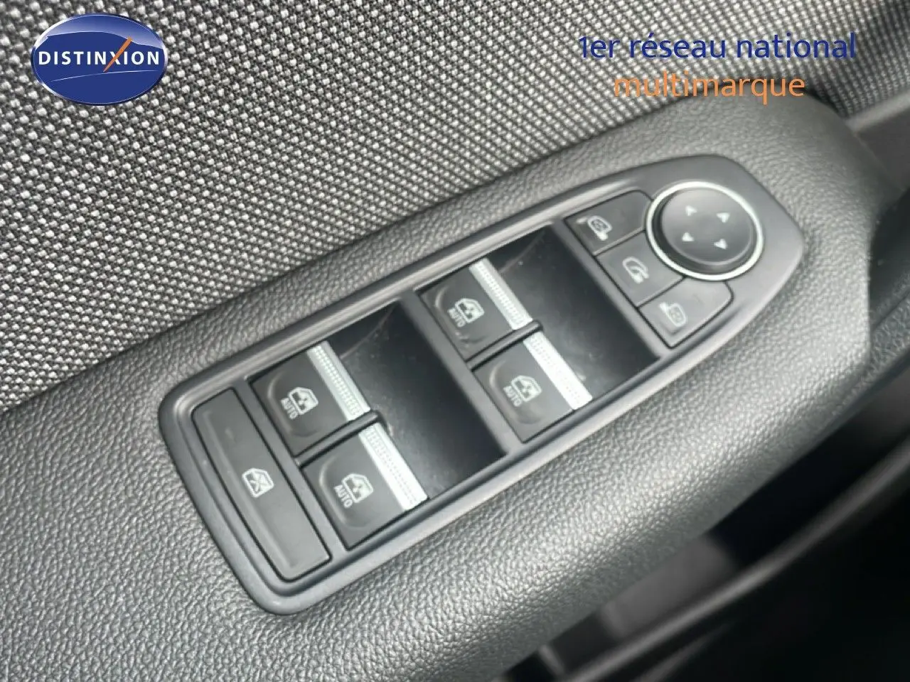 Gros plan sur les commandes des vitres électriques et rétroviseurs sur la porte côté conducteur d’un Renault Captur gris cassiopée métal avec toit noir.