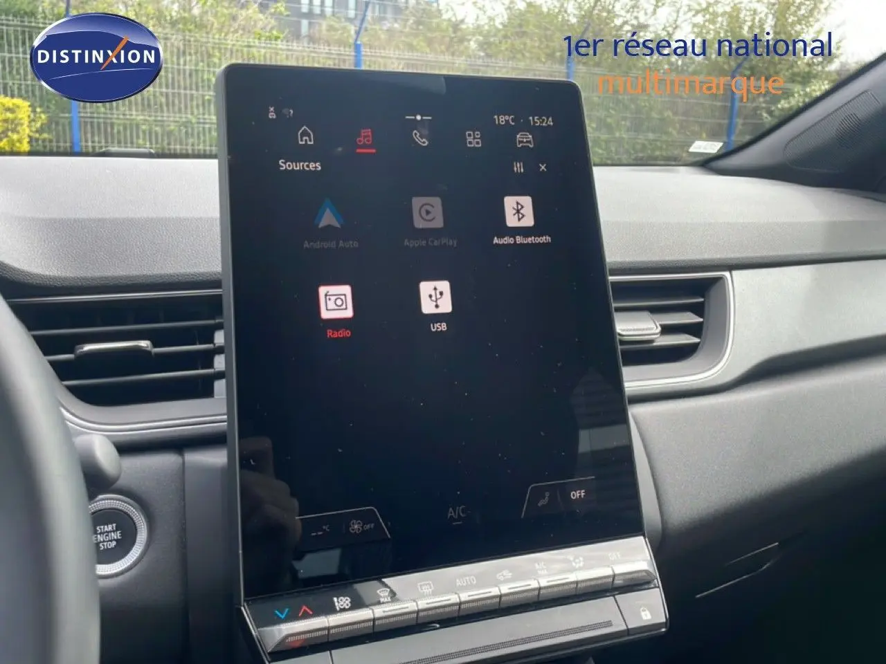 Vue intérieure centrée sur l'écran tactile vertical du tableau de bord du Renault Captur 2025, avec démarrage sans clé visible.