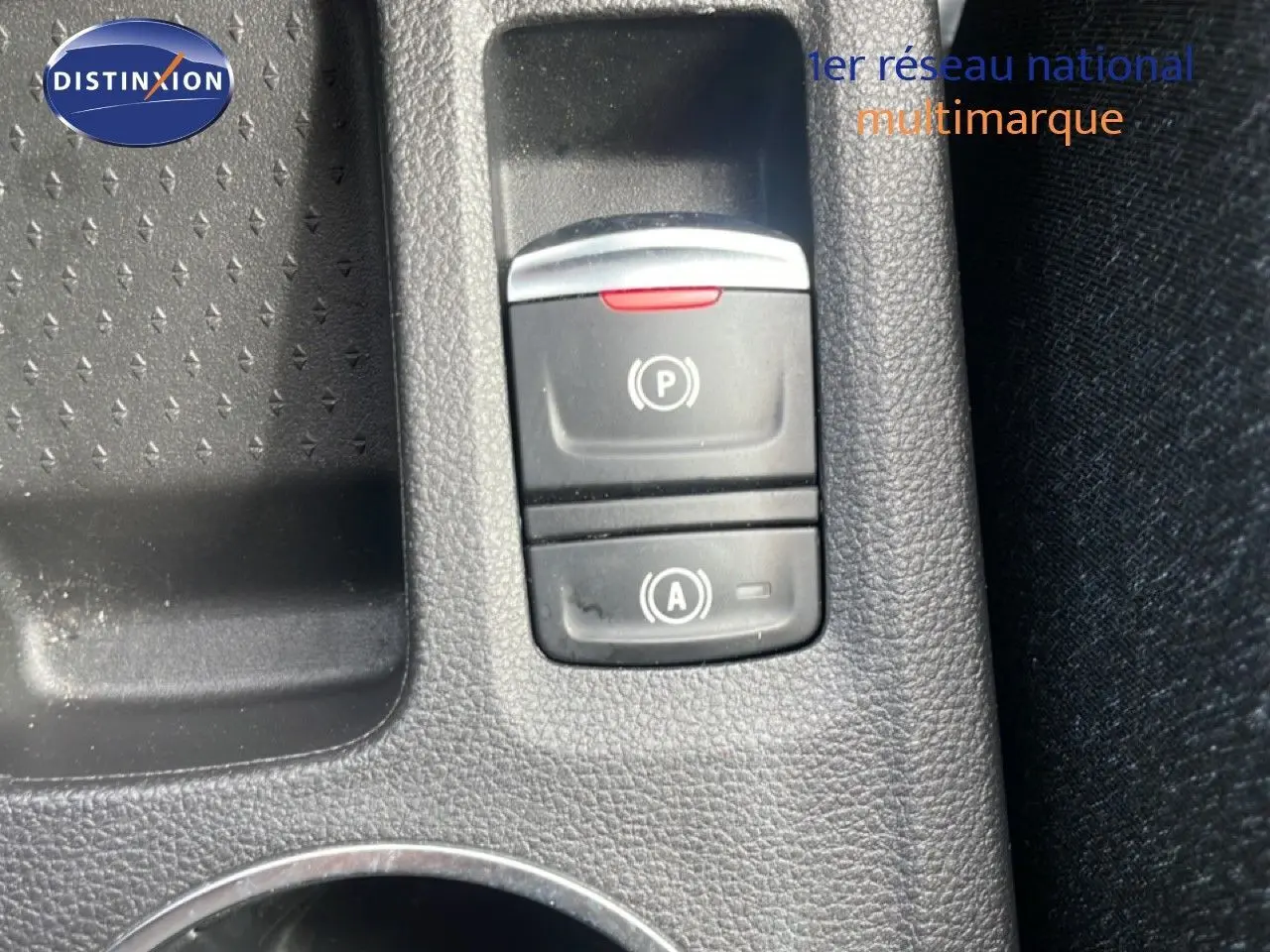 Gros plan sur les commandes de frein à main électronique et d'arrêt automatique du moteur du Renault Captur gris Cassiopée métal.