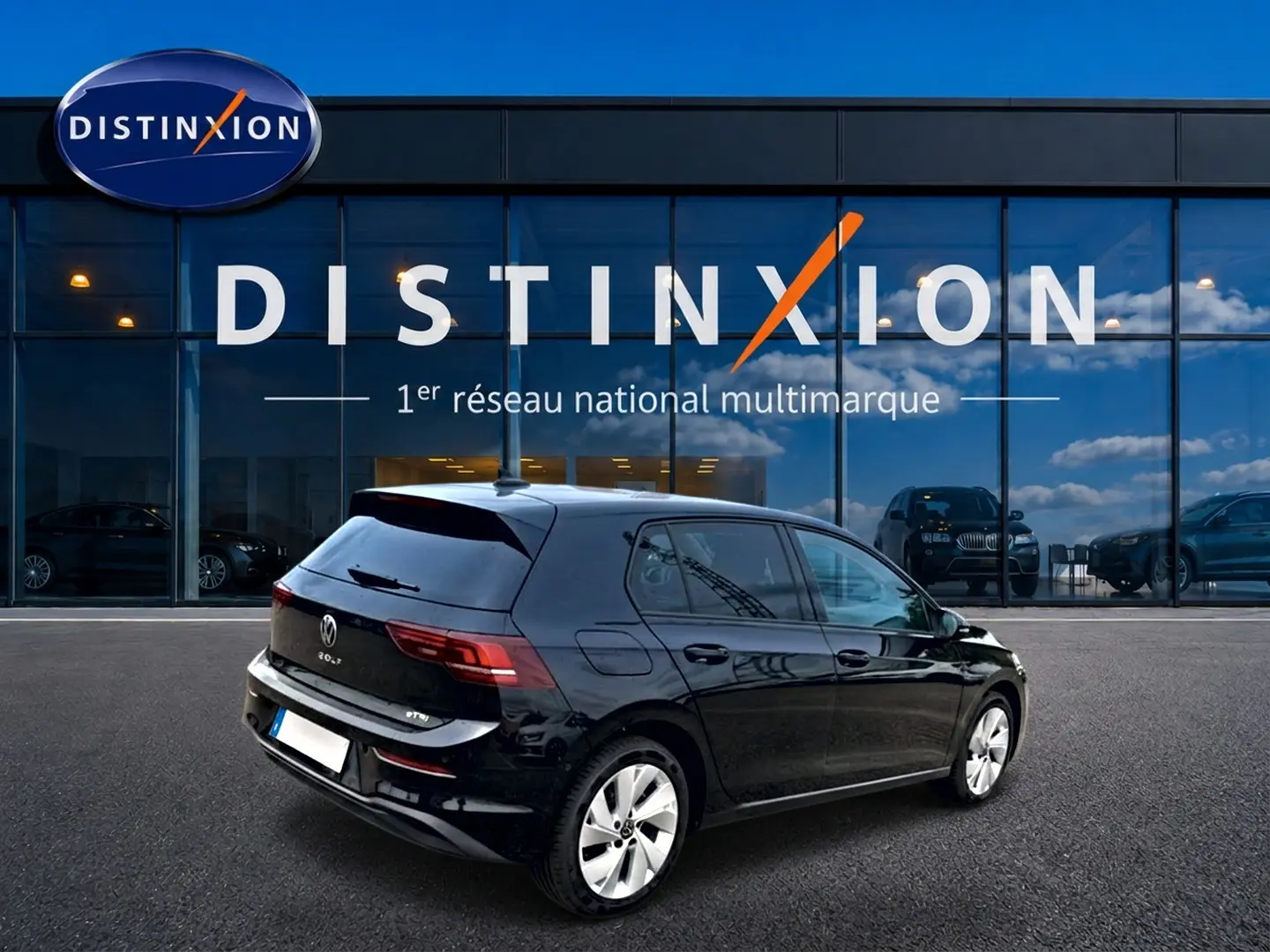 Vue 3/4 arrière droite d'une Volkswagen Golf noire 2026, avec jantes alu et vitres arrière surteintées devant un showroom Distinxion.
