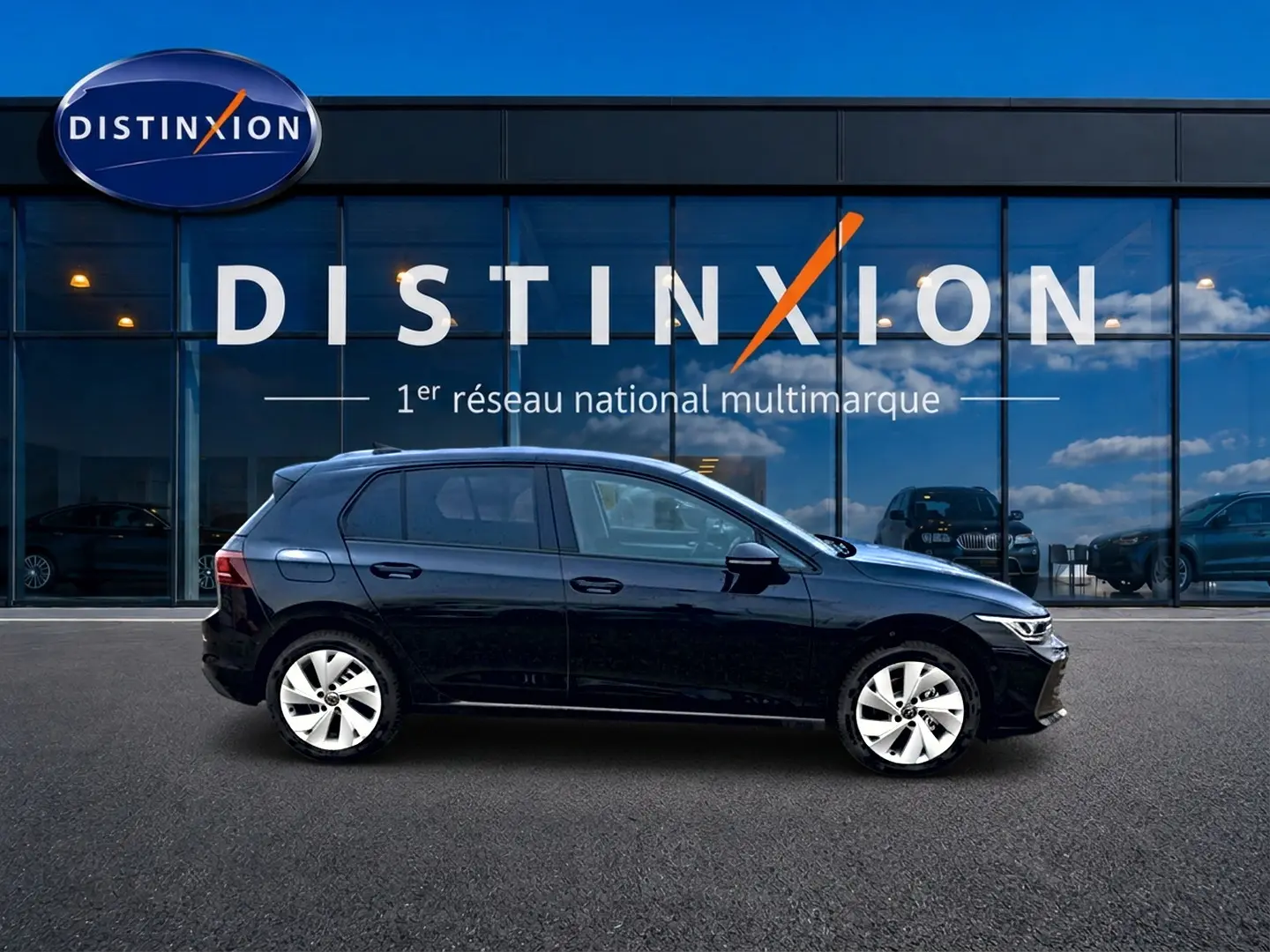 Vue de profil côté gauche d'une Volkswagen Golf noire 2026 garée devant une vitrine avec logo Distinxion.