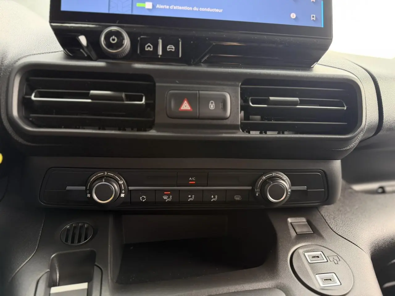 Vue rapprochée du tableau de bord noir du Citroën Berlingo 2026, montrant les aérateurs et commandes de climatisation.