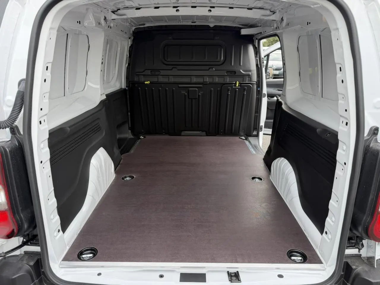Vue arrière du Citroën Berlingo Van XL blanc Icy, montrant l’espace de chargement avec plancher bois antidérapant.