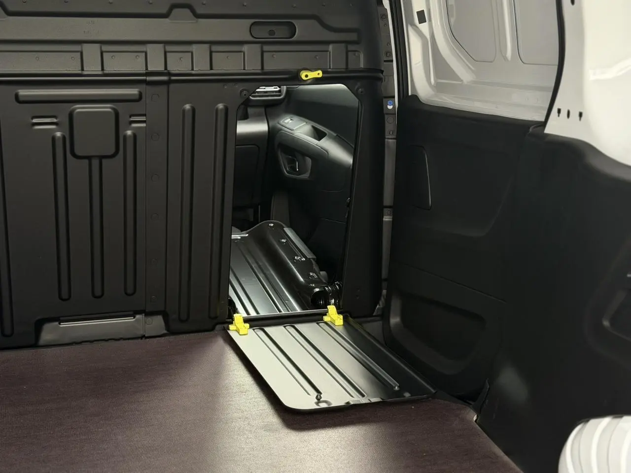 Intérieur du Citroën Berlingo Van XL blanc, vue sur le plancher bois antidérapant et cloison tôlée noire côté droit.