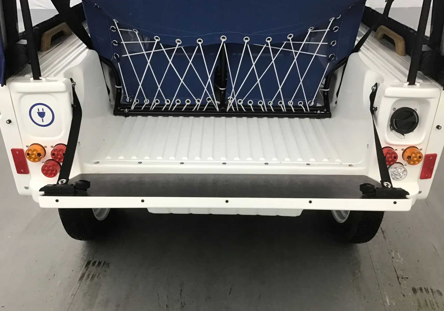 Vue arrière ouverte du MLT E-STORY ICONE blanc et bleu, mettant en valeur la banquette avec filet élastique et coffre spacieux.