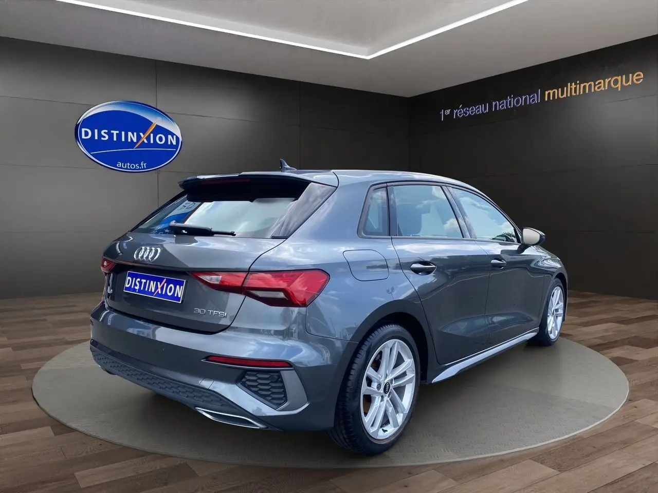 Audi A3 Sportback gris Daytona vue 3/4 arrière droit, mettant en valeur ses feux LED et jantes alliage.