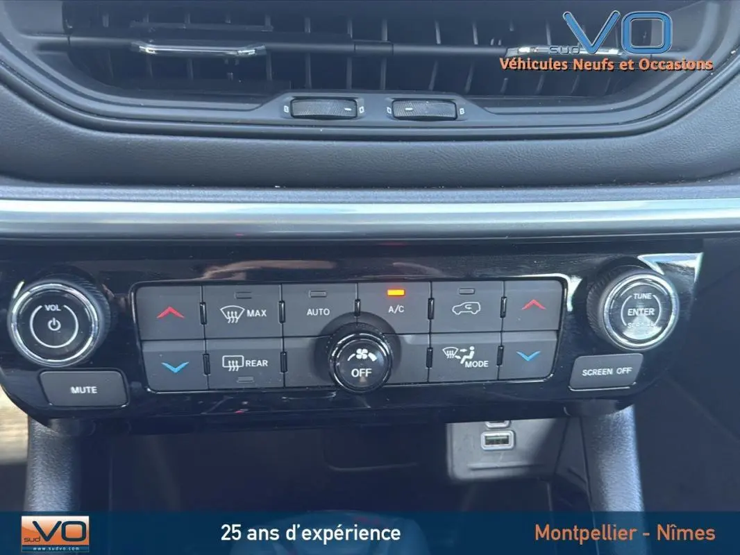 Panneau de climatisation et commandes centrales du Jeep Compass blanc 2024 avec écran tactile et prise USB visible.