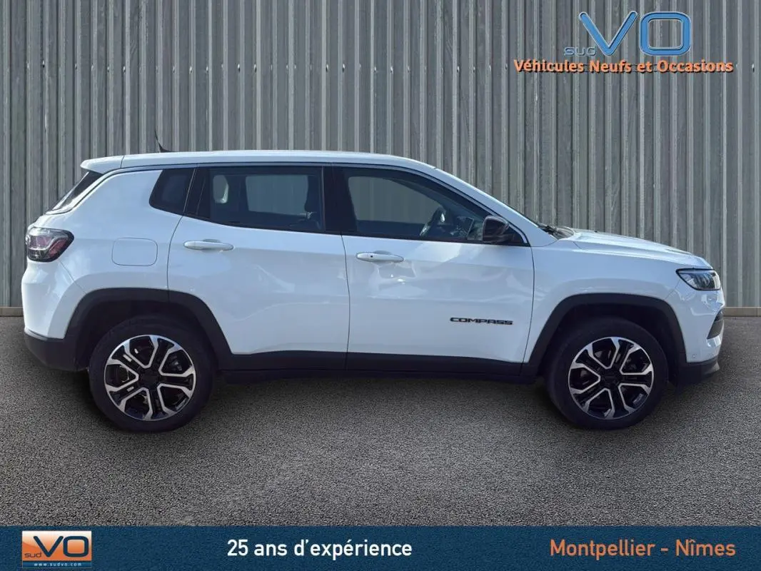 Vue latérale droite d'un Jeep Compass blanc 2024 avec jantes alliage 18 pouces et logo distinctif sur la porte