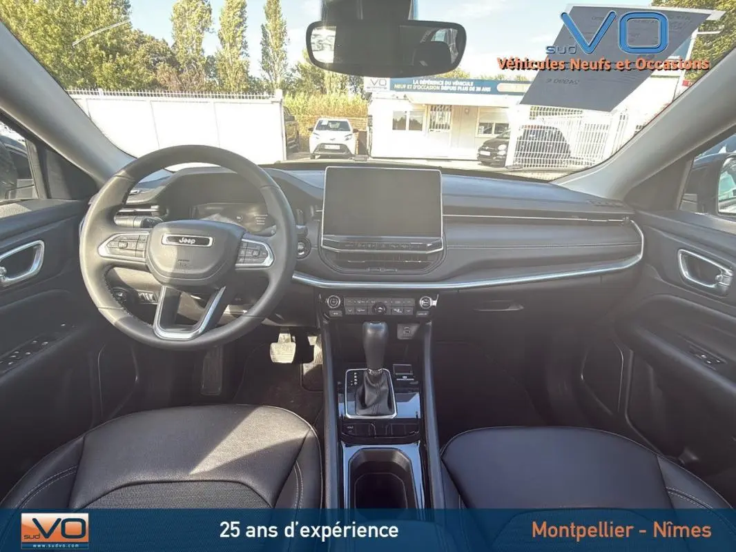 Vue intérieure avant du Jeep Compass 2024 avec tableau de bord noir et écran tactile central.