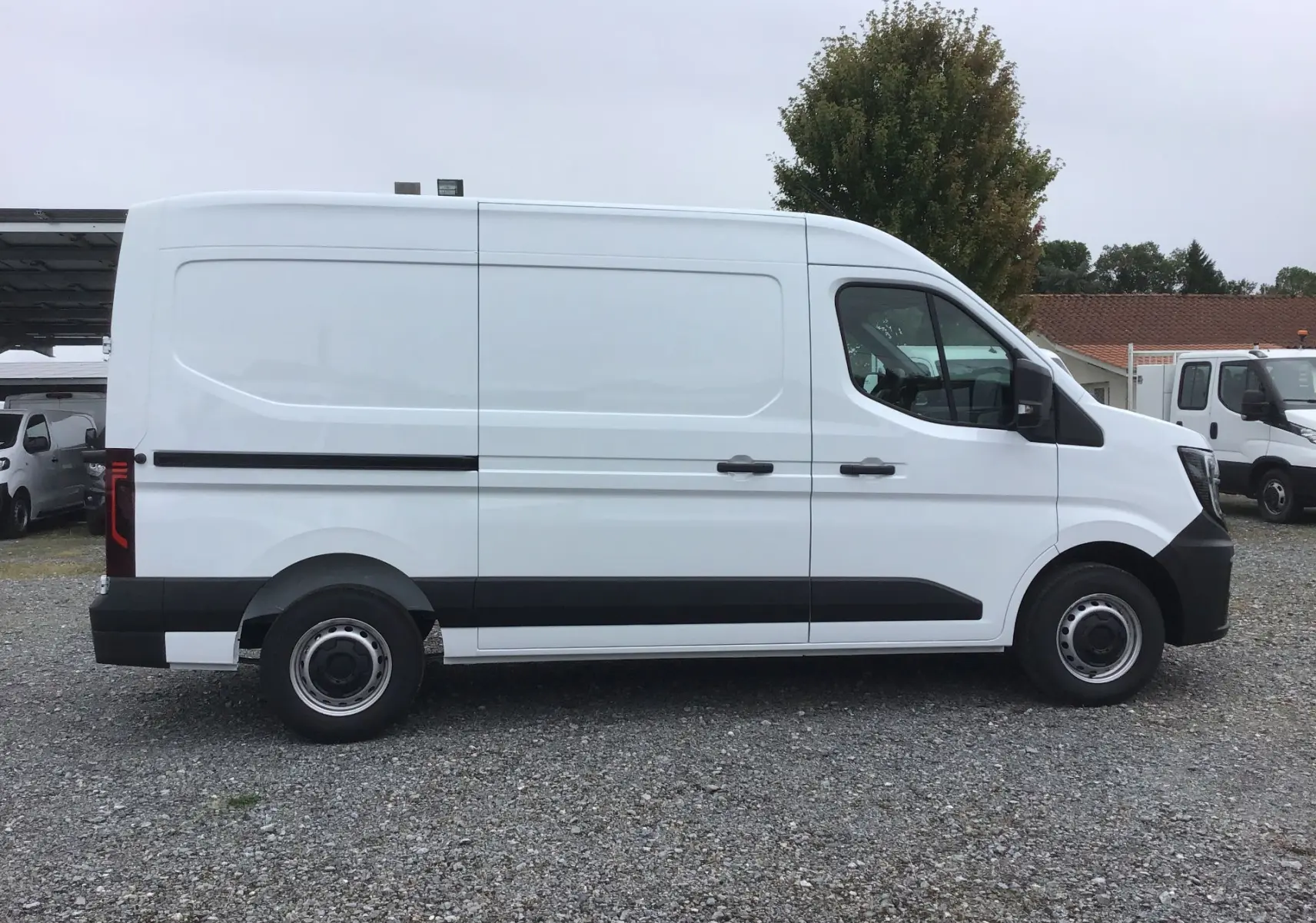 Profil droit d'un utilitaire blanc Renault Master L2H2 2025, avec porte latérale coulissante et jantes acier noires.