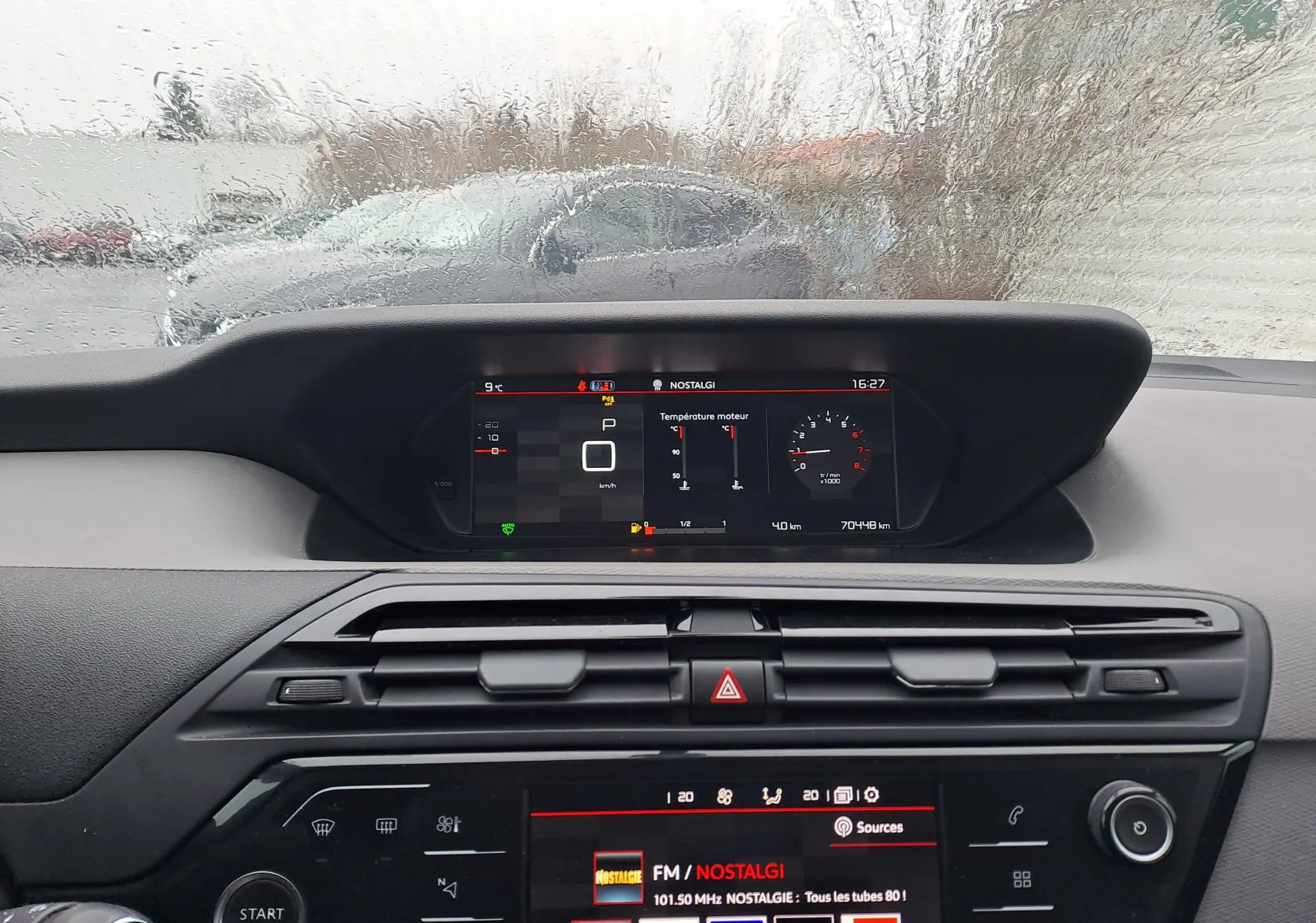 Vue intérieure du tableau de bord noir de la Citroën C4 Spacetourer blanche, avec affichage numérique et écran multimédia allumé.