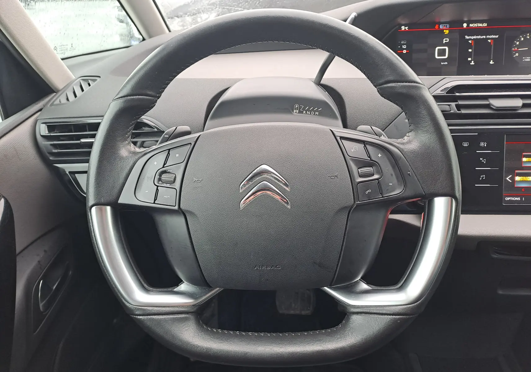 Vue centrée sur le volant noir du Citroën C4 Spacetourer 2018 avec commandes intégrées et tableau de bord numérique en arrière-plan.