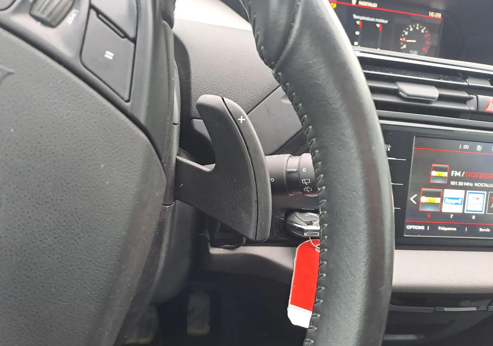 Gros plan sur la palette de changement de vitesse droite du volant dans l'habitacle noir d'une Citroën C4 Spacetourer blanche.