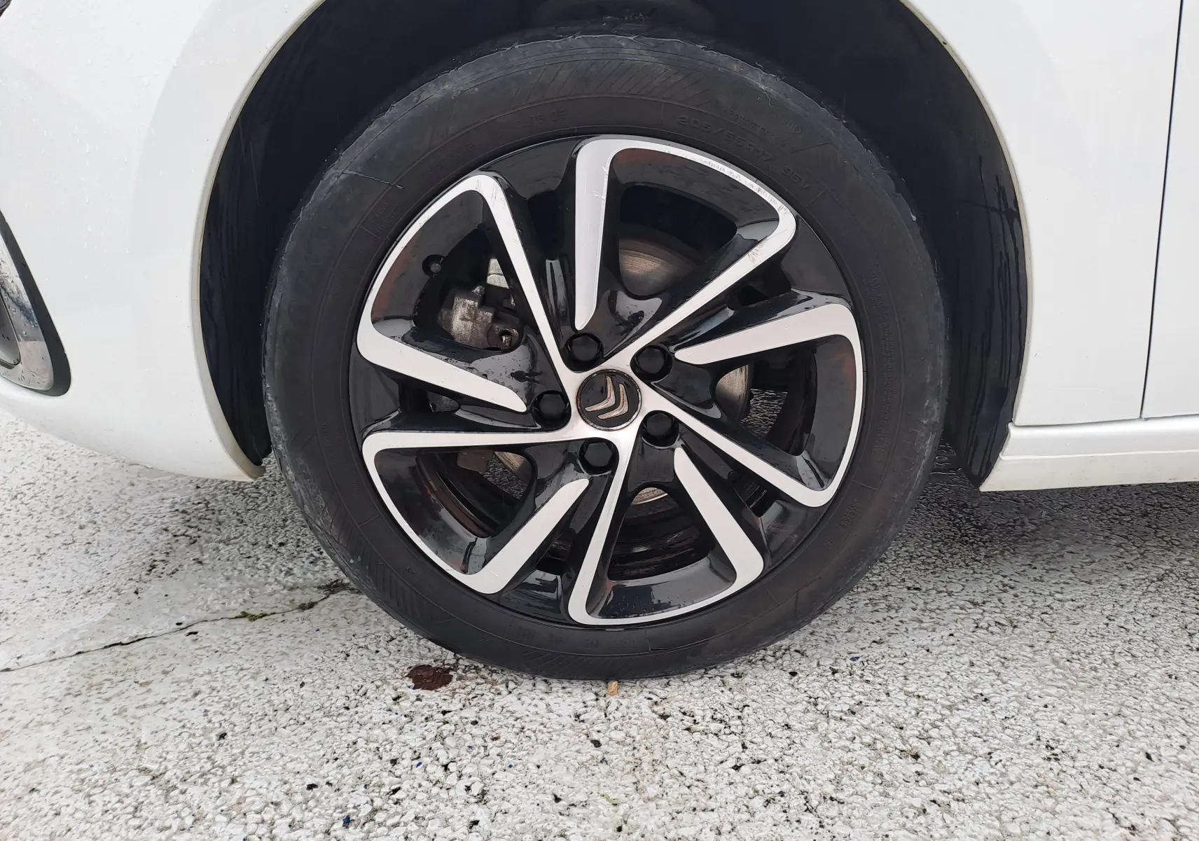 Gros plan sur la roue avant gauche d'une Citroën C4 Spacetourer blanche avec jante alliage noire et argentée.