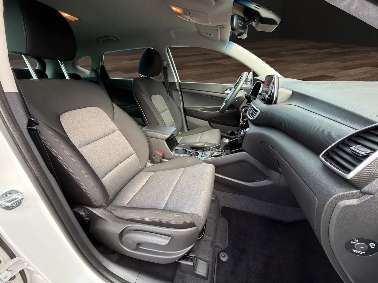 Vue intérieure côté droit du Hyundai Tucson blanc polar 2020, sièges tissu noir et gris, tableau de bord moderne.