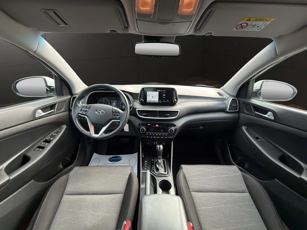 Vue intérieure avant du Hyundai Tucson 2020, tableau de bord et sièges tissu noir avec console centrale et écran tactile.