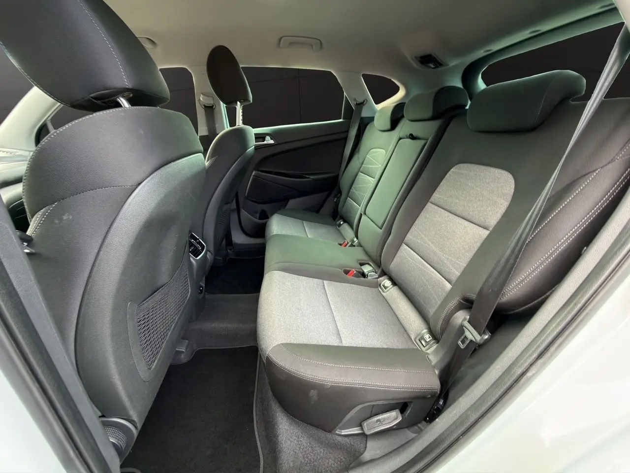 Vue intérieure côté droit montrant la banquette arrière en tissu noir et gris du Hyundai Tucson blanc polar 2020.