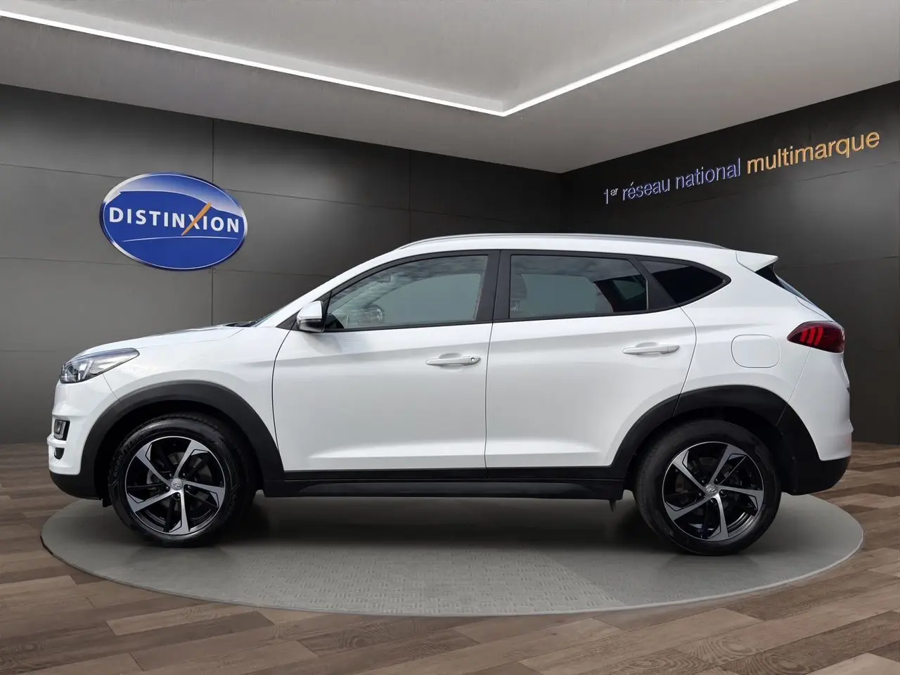 Vue de profil côté gauche du Hyundai Tucson blanc polar 2020 avec jantes 18 pouces bicolores et détails noirs contrastants.