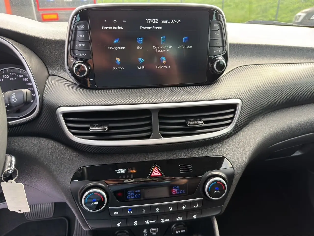 Vue intérieure du tableau de bord du Hyundai Tucson blanc Polar 2020, avec écran tactile central et commandes de climatisation.