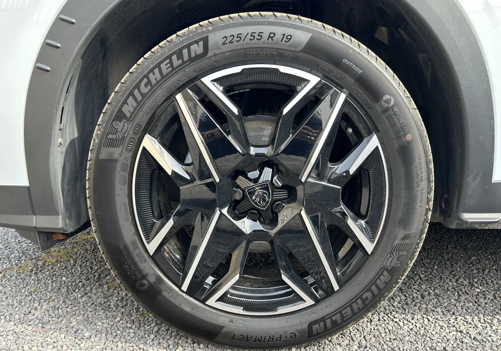 Gros plan sur la roue avant gauche d’un Peugeot 3008 blanc Okenite avec jante noire et argentée, pneu Michelin.