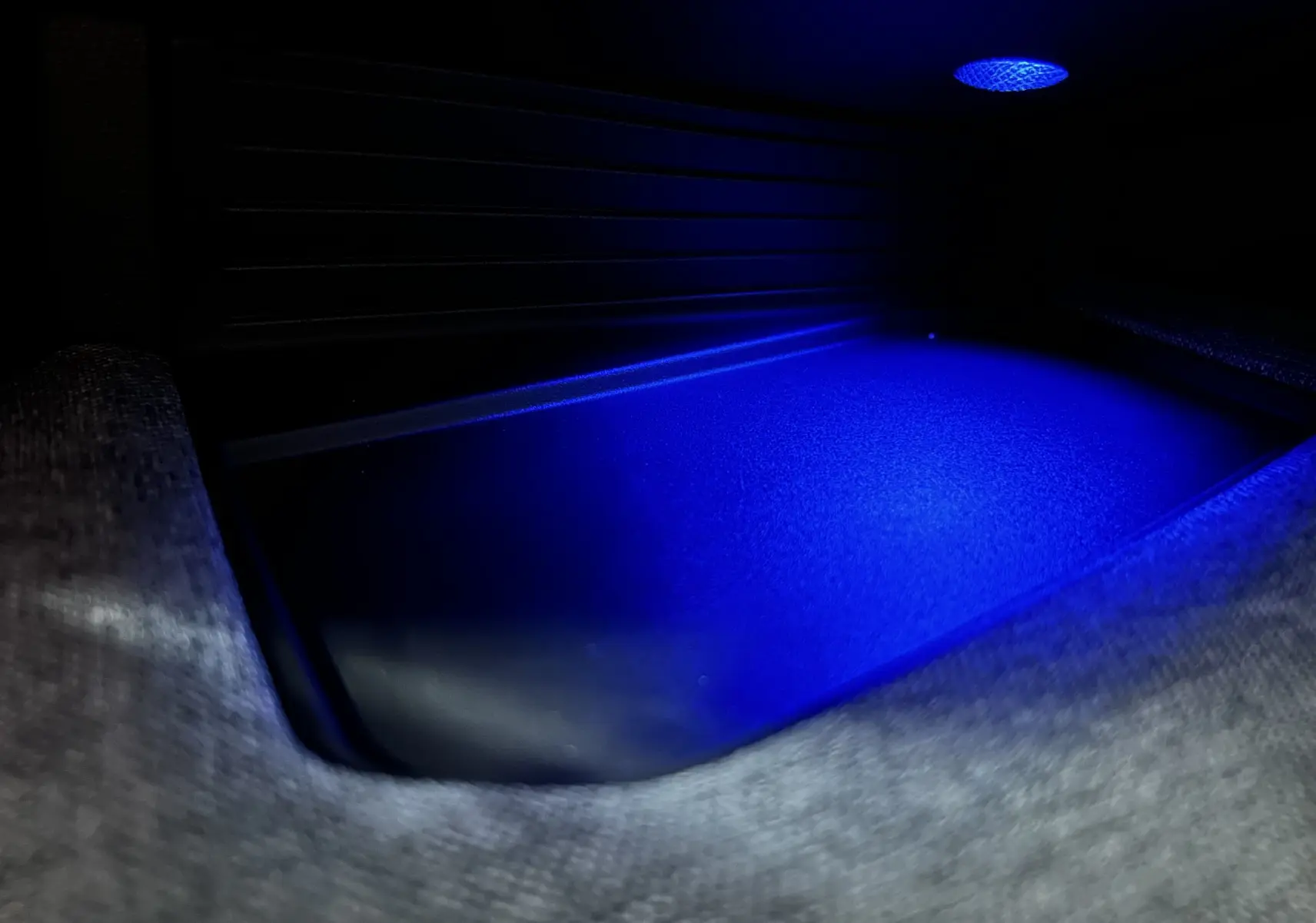 Gros plan sur l'éclairage d'ambiance bleu dans le compartiment de rangement intérieur du Peugeot 3008 blanc hybride.