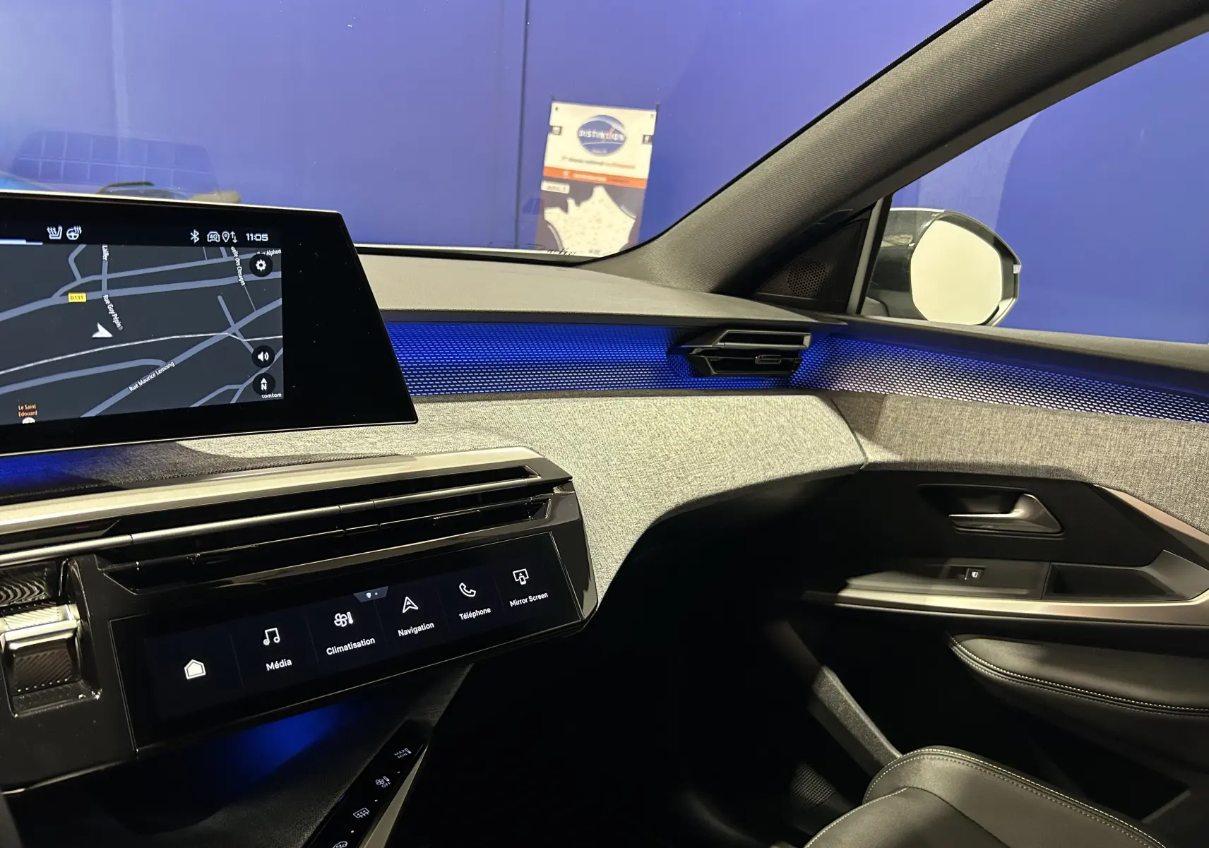 Vue intérieure côté passager du tableau de bord du Peugeot 3008 III Hybrid 145 avec éclairage d'ambiance bleu et écran tactile de navigation.