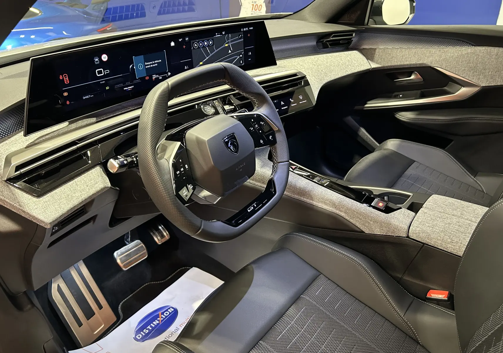 Intérieur du Peugeot 3008 hybride 2025 vu côté conducteur, avec volant cuir noir et tableau de bord numérique large.