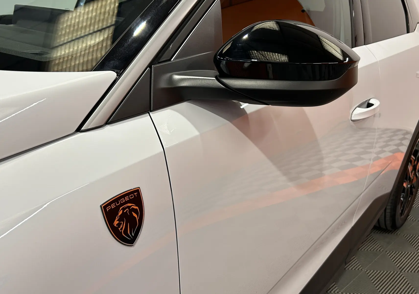Gros plan sur le côté gauche blanc okenite du Peugeot 3008 III Hybrid avec rétroviseur noir brillant et logo lion orange.
