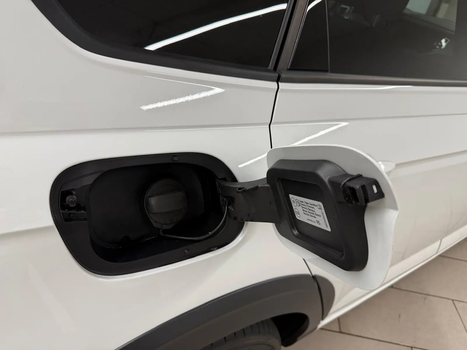 Vue rapprochée du côté gauche arrière d’un Volkswagen Taigo blanc pur avec trappe de carburant ouverte.