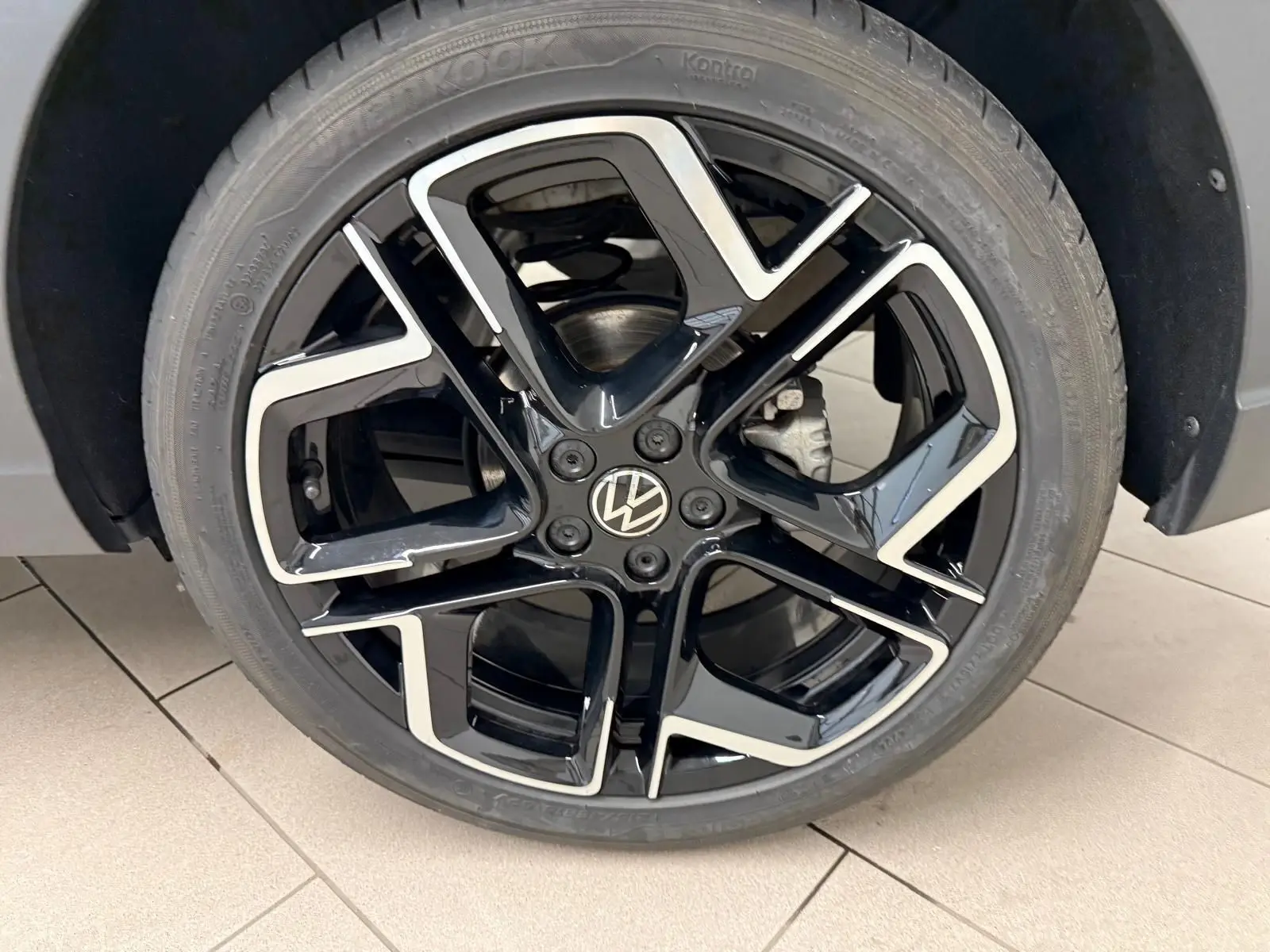 Gros plan sur la jante alliage noire et argentée 18 pouces avec logo Volkswagen au centre, montée sur pneu Hankook.