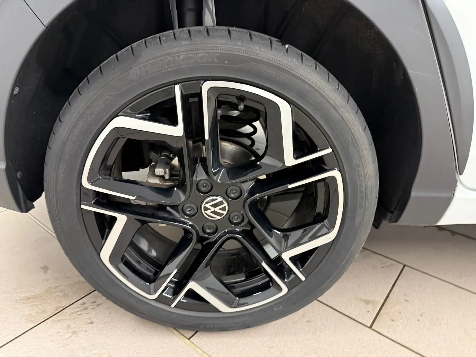 Gros plan sur la jante alliage noire et argentée 18 pouces du côté avant droit du Volkswagen Taigo blanc toit noir.