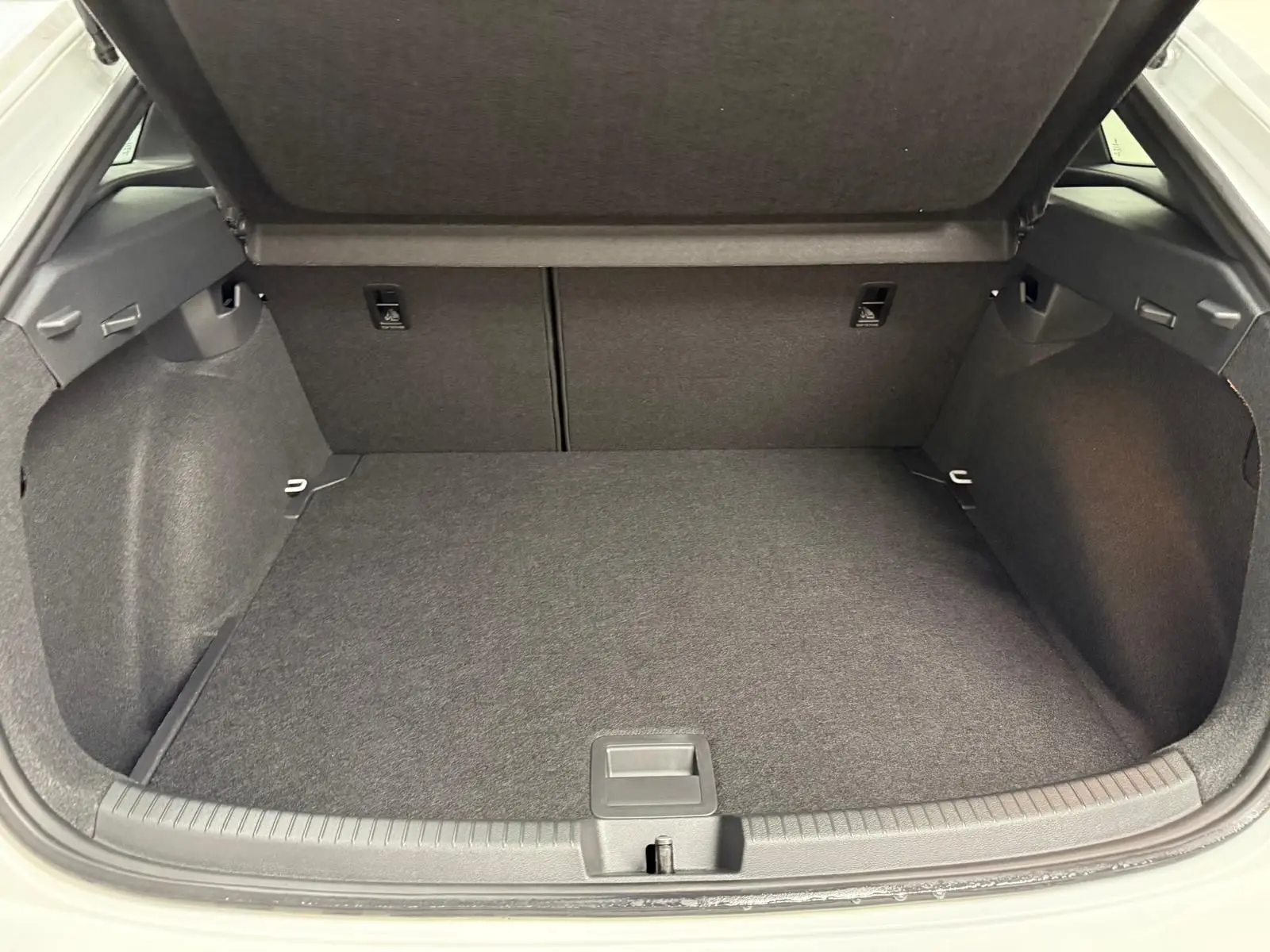 Coffre ouvert du Volkswagen Taigo 2025, vue arrière, espace de chargement propre et tapis gris foncé.
