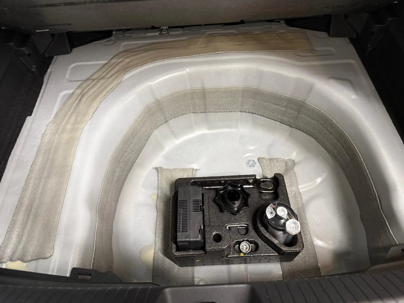 Vue plongeante sur le coffre de la Volkswagen Taigo 2025, montrant le rangement sous plancher avec kit de dépannage.