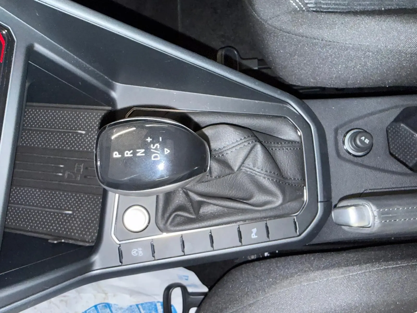 Gros plan sur le levier de vitesses automatique noir avec soufflet cuir dans le Volkswagen Taigo blanc toit noir.