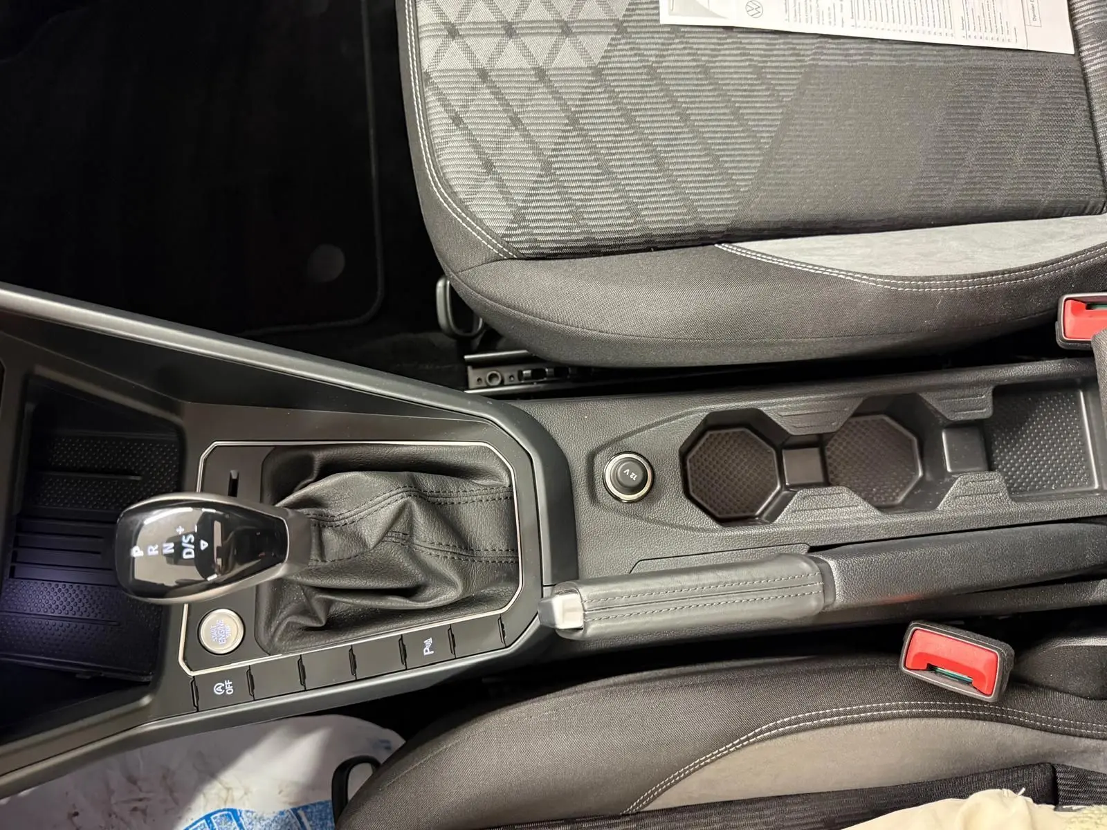 Vue plongeante sur la console centrale et levier de vitesse cuir d'une Volkswagen Taigo blanc pur toit noir.
