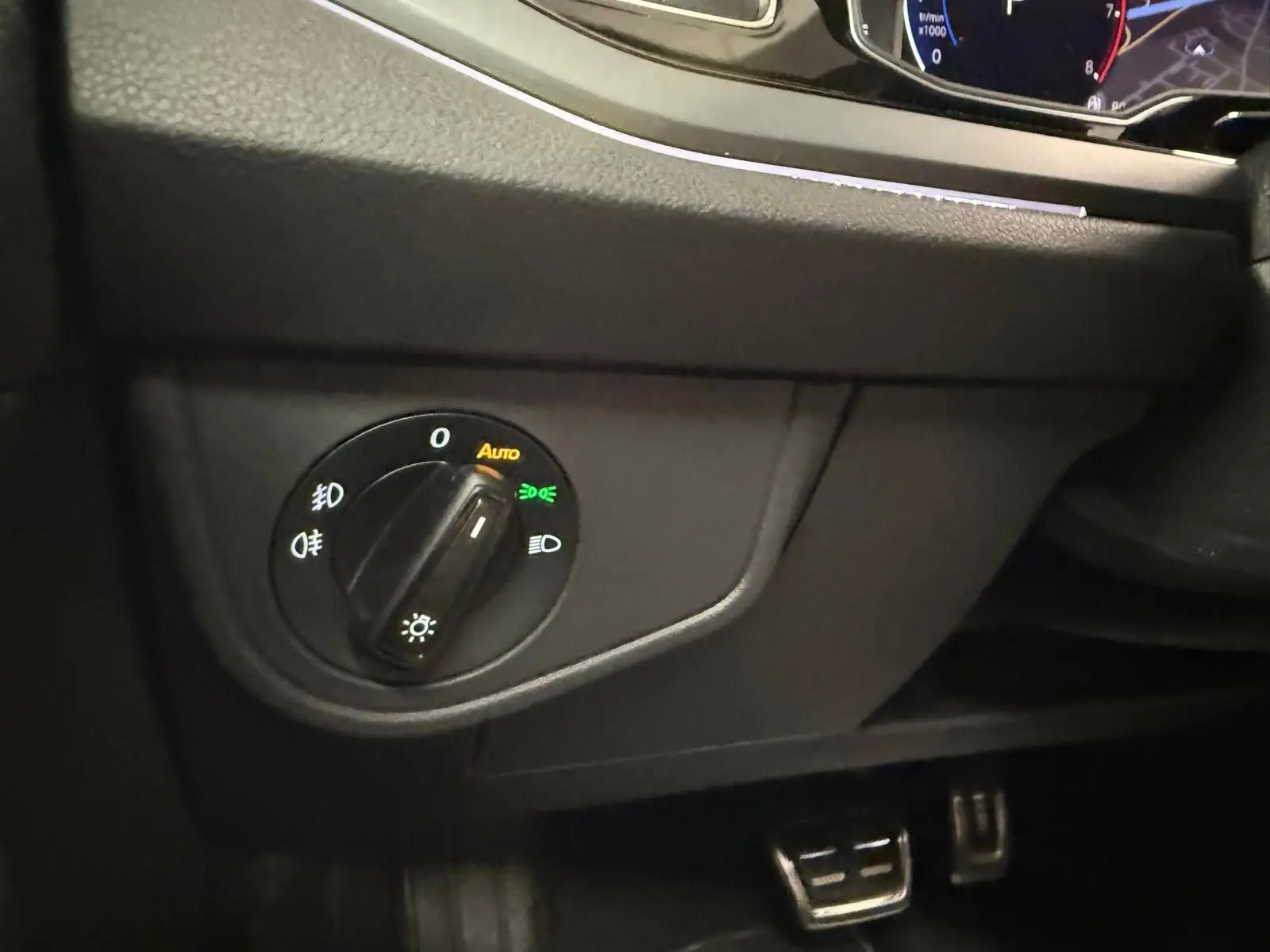 Gros plan sur le bouton de commande des phares du Volkswagen Taigo 2025, intérieur noir avec éclairage LED.